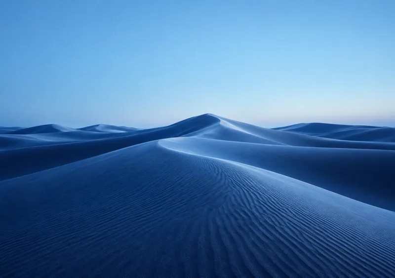 Powder-blue dune crests flow into indigo shadows beneath an open sky. — Inner Display